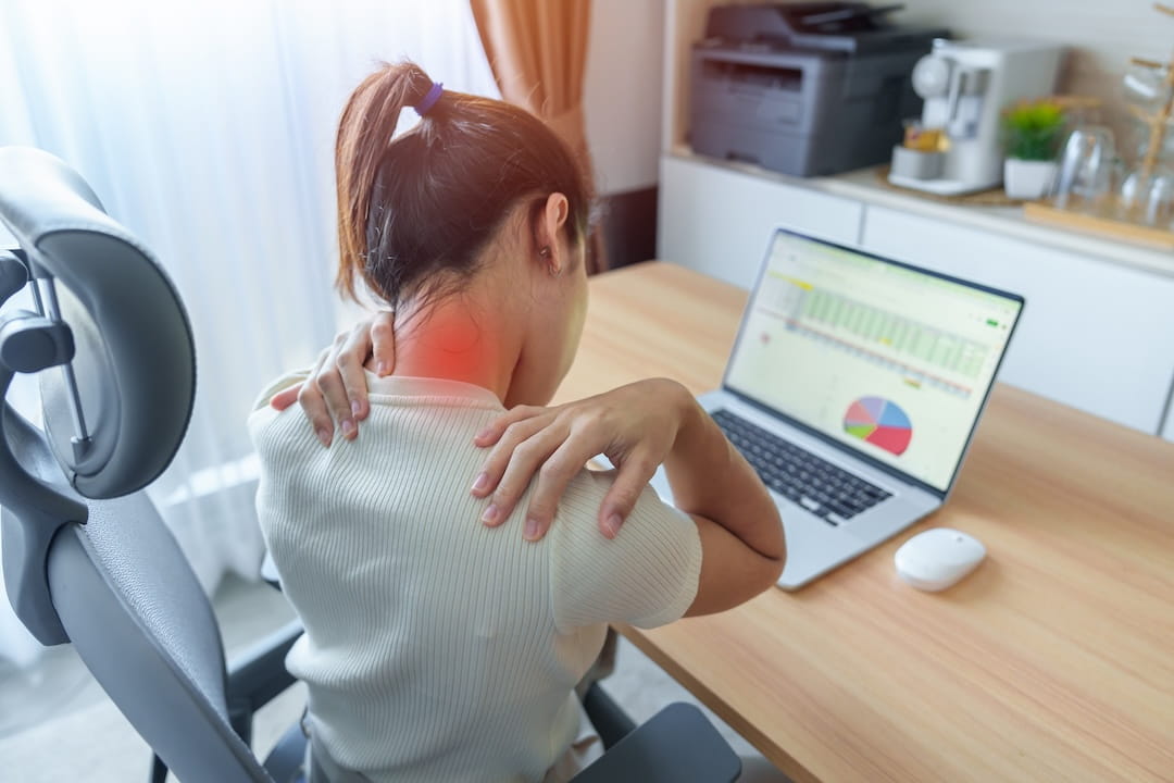 Office worker experiencing neck and shoulder pain from prolonged desk work