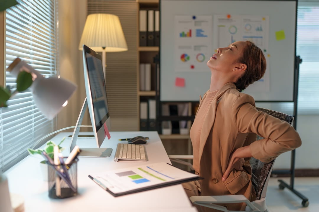 Stressed office worker experiencing lower back pain and tension from chronic stress
